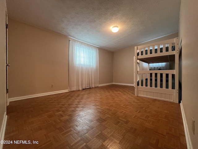 unfurnished bedroom featuring a textured ceiling and parquet floors