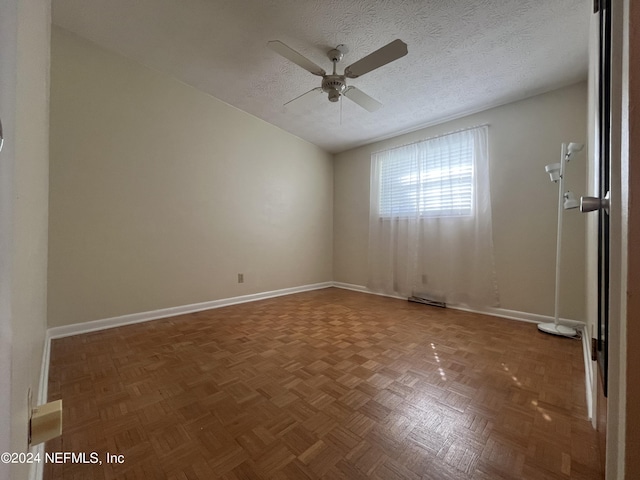 empty room featuring ceiling fan, dark parquet floors, and a textured ceiling