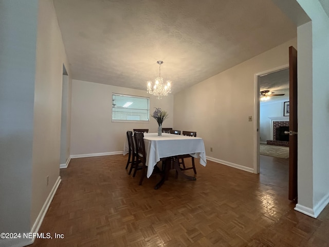 dining room featuring a fireplace, an inviting chandelier, a textured ceiling, and dark parquet flooring