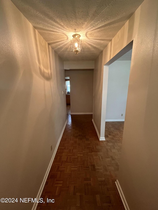 hallway featuring dark parquet floors and a textured ceiling