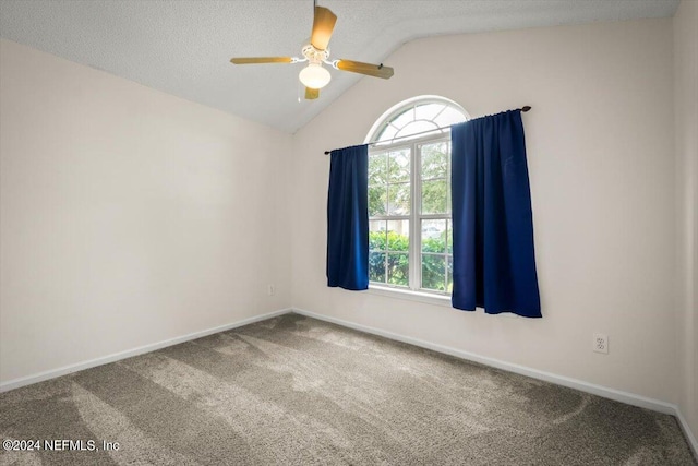 carpeted spare room with a wealth of natural light, vaulted ceiling, a textured ceiling, and ceiling fan