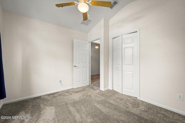 unfurnished bedroom featuring ceiling fan, carpet floors, a textured ceiling, vaulted ceiling, and a closet