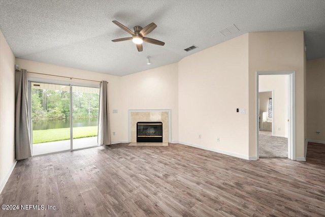 unfurnished living room with hardwood / wood-style flooring, ceiling fan, a premium fireplace, and a textured ceiling