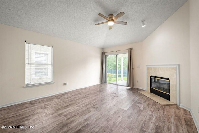 unfurnished living room featuring lofted ceiling, a premium fireplace, ceiling fan, a textured ceiling, and light wood-type flooring