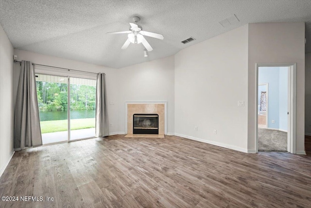 unfurnished living room with ceiling fan, a premium fireplace, hardwood / wood-style floors, and a textured ceiling