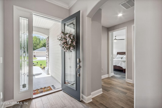 entryway with hardwood / wood-style floors, ceiling fan, and crown molding