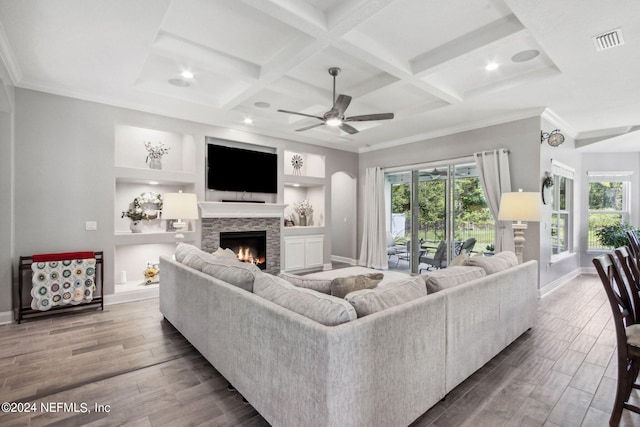 living room with built in shelves, ceiling fan, a fireplace, and coffered ceiling