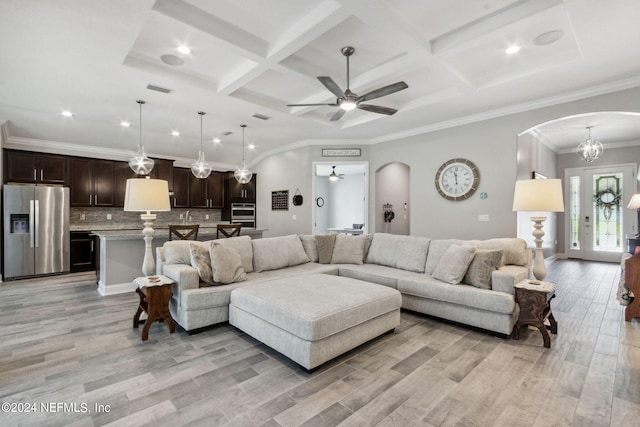 living room with ceiling fan with notable chandelier, ornamental molding, coffered ceiling, and light wood-type flooring