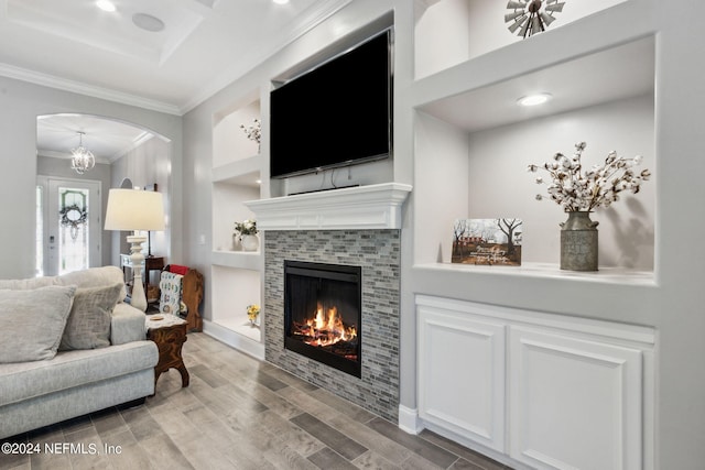 living room with a fireplace, hardwood / wood-style flooring, ornamental molding, and a notable chandelier