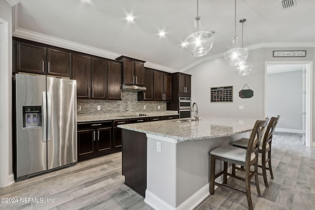 kitchen featuring a kitchen island with sink, light stone countertops, appliances with stainless steel finishes, decorative light fixtures, and dark brown cabinets