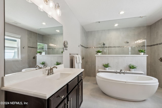 bathroom featuring shower with separate bathtub, vanity, tile patterned floors, and tile walls