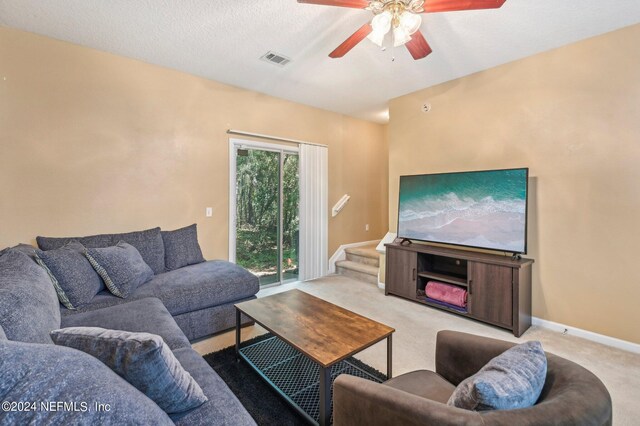 living room featuring light carpet, a textured ceiling, and ceiling fan