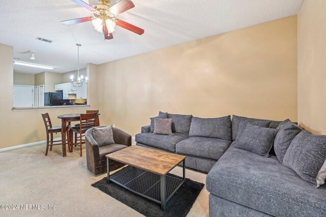 living room featuring light carpet, a textured ceiling, and ceiling fan with notable chandelier