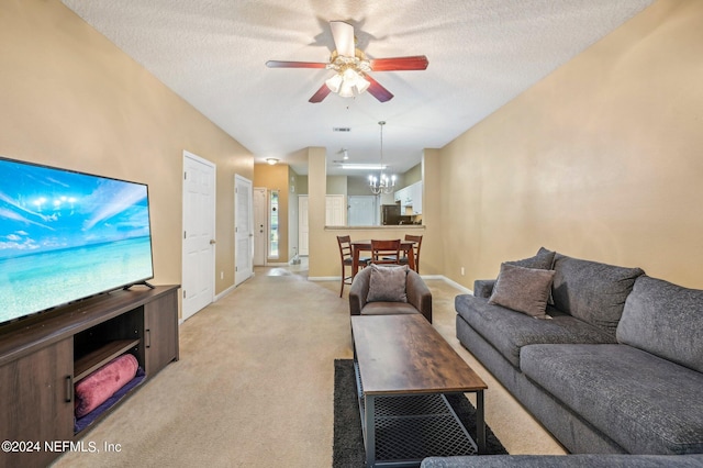 carpeted living room with a textured ceiling, ceiling fan with notable chandelier, and a healthy amount of sunlight