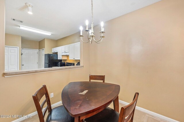 carpeted dining space featuring a notable chandelier