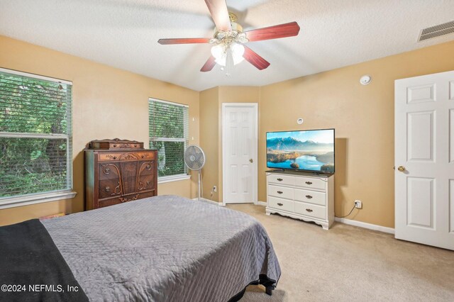 bedroom with light carpet, multiple windows, and ceiling fan