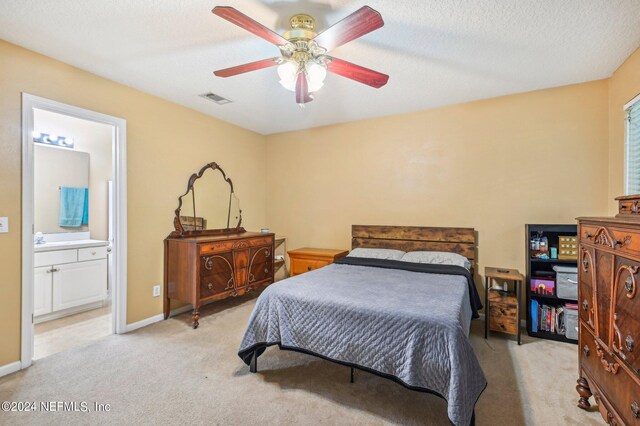 carpeted bedroom with ensuite bathroom, a textured ceiling, and ceiling fan