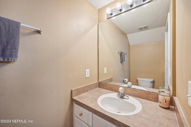 bathroom with toilet, vanity, and a textured ceiling