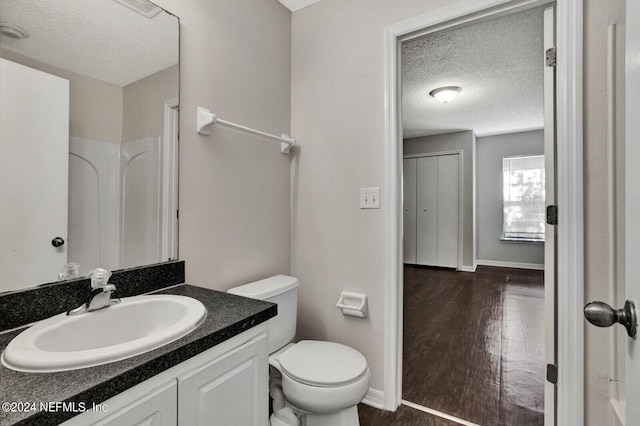 bathroom featuring a textured ceiling, vanity, a shower, wood-type flooring, and toilet