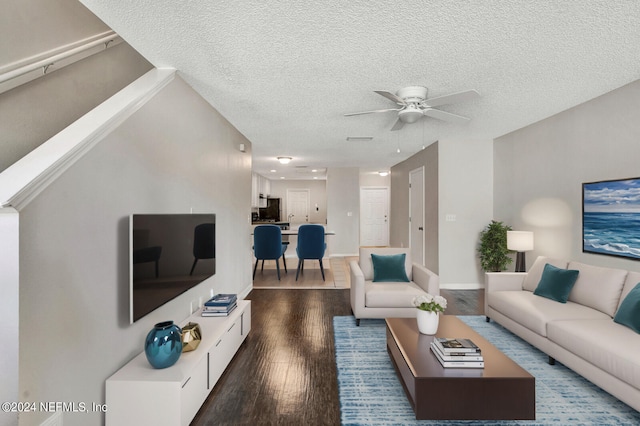 living room featuring dark hardwood / wood-style floors, ceiling fan, and a textured ceiling