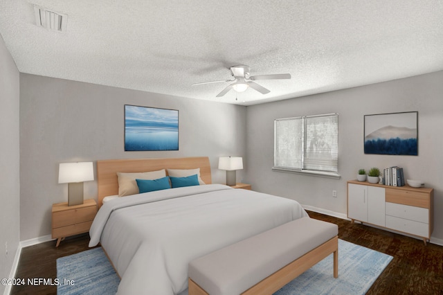 bedroom with ceiling fan, dark hardwood / wood-style flooring, and a textured ceiling