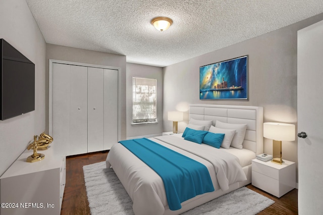 bedroom featuring a closet, dark wood-type flooring, and a textured ceiling