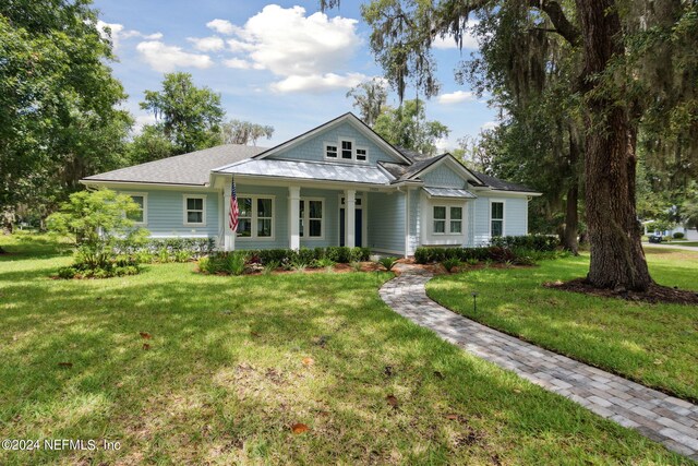 view of front of property featuring a standing seam roof, metal roof, a front lawn, and a porch