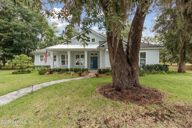 view of front of property featuring a porch, a front yard, a standing seam roof, and metal roof