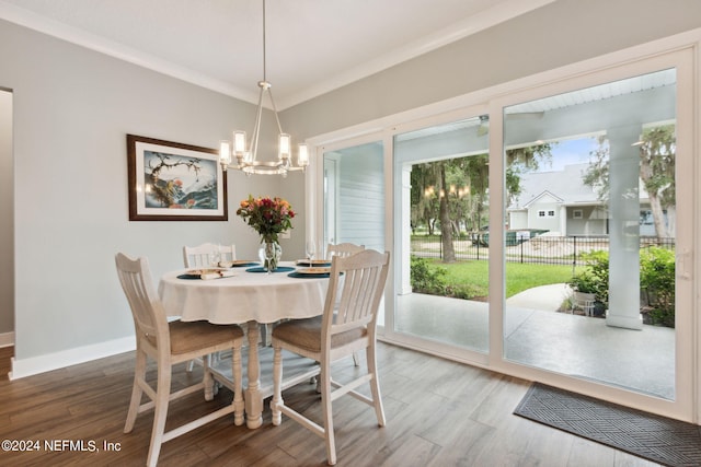 dining area with ornamental molding, an inviting chandelier, wood finished floors, and baseboards