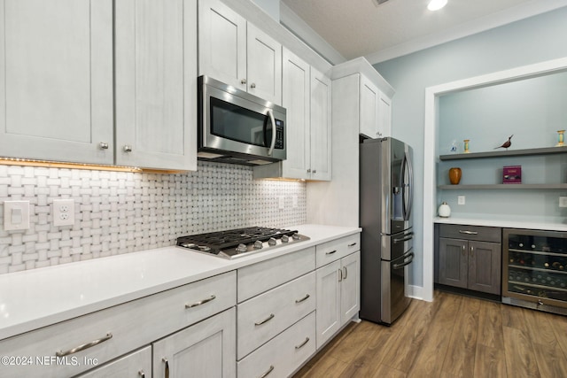 kitchen with stainless steel appliances, light countertops, decorative backsplash, wood finished floors, and beverage cooler