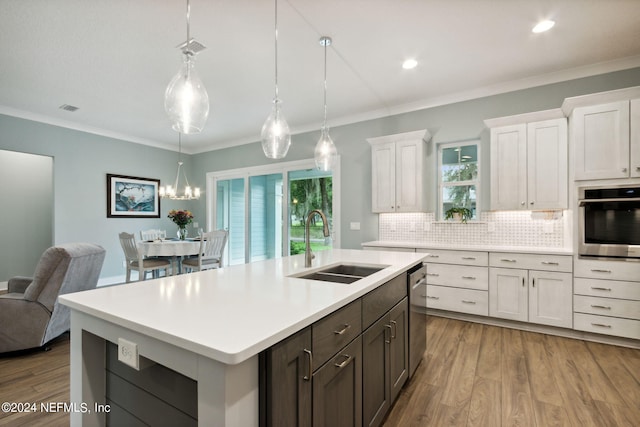 kitchen with stainless steel appliances, wood finished floors, a sink, light countertops, and decorative backsplash