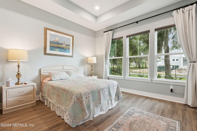 bedroom with multiple windows, wood finished floors, and baseboards