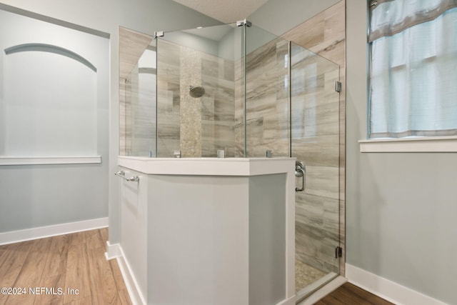 bathroom featuring a shower stall, baseboards, and wood finished floors