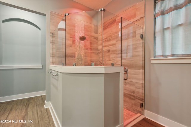 full bathroom featuring a stall shower, baseboards, and wood finished floors