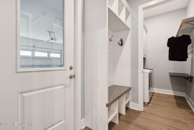 mudroom featuring wood finished floors, washing machine and clothes dryer, and baseboards