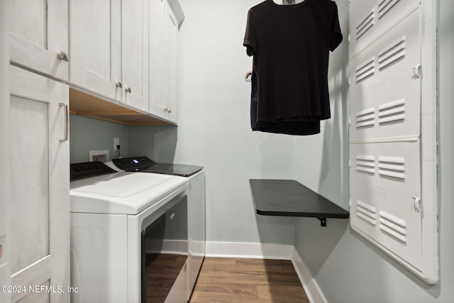 laundry room featuring baseboards, cabinet space, washing machine and clothes dryer, and wood finished floors