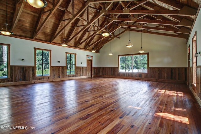 unfurnished living room with wainscoting, wood-type flooring, and beam ceiling