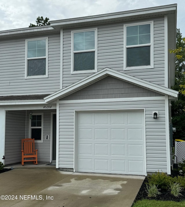 view of front facade with a garage, covered porch, and concrete driveway