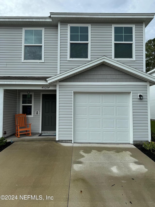 view of front of house featuring a porch, concrete driveway, and an attached garage