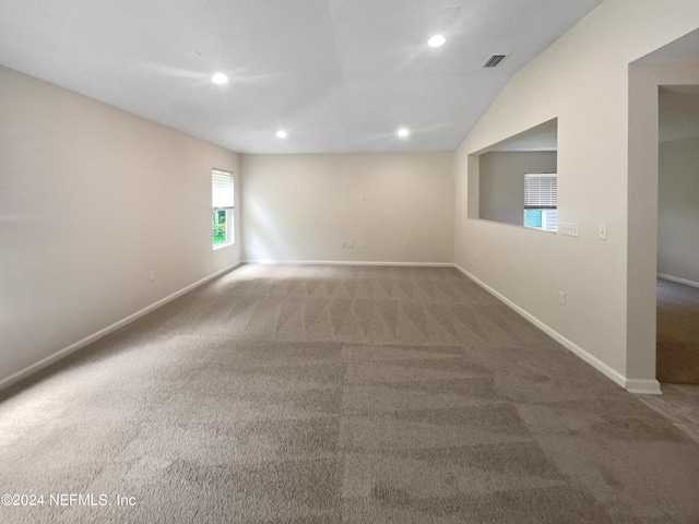 carpeted spare room with lofted ceiling