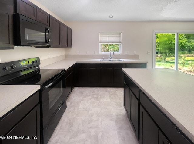 kitchen with dark brown cabinets, sink, a healthy amount of sunlight, and black appliances