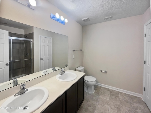 bathroom featuring vanity, toilet, a shower with door, and a textured ceiling