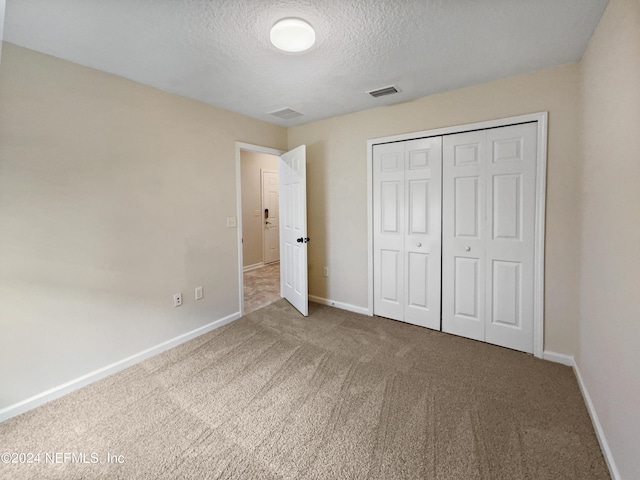 unfurnished bedroom with carpet, a textured ceiling, and a closet