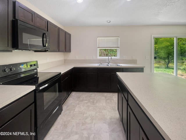 kitchen featuring a wealth of natural light, sink, black appliances, and a textured ceiling