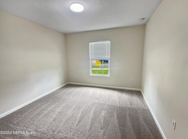 carpeted empty room with a textured ceiling