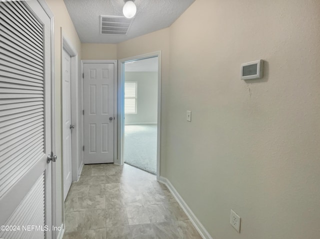 hallway with a textured ceiling