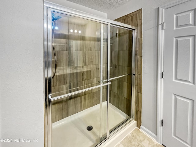 bathroom featuring tile patterned flooring, a textured ceiling, and a shower with door