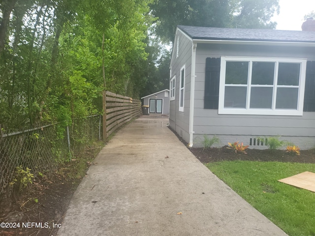 view of home's exterior with an outbuilding, fence, driveway, crawl space, and roof with shingles