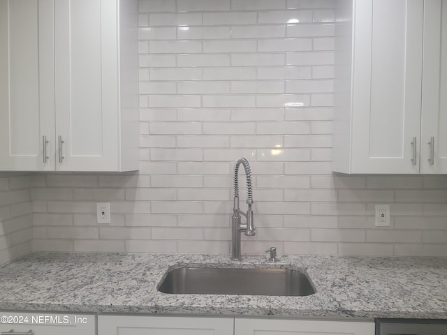 kitchen with tasteful backsplash, a sink, and white cabinetry