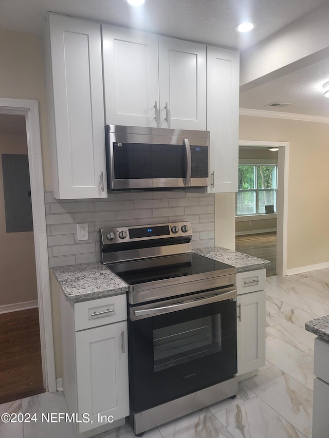 kitchen featuring crown molding, appliances with stainless steel finishes, white cabinets, and backsplash